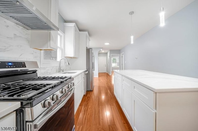 125 Birch St, Bloomfield Twp, NJ 07003 - kitchen featuring appliances with stainless steel finishes, wall chimney range hood, white cabinets, pendant lighting, and light wood finished floors