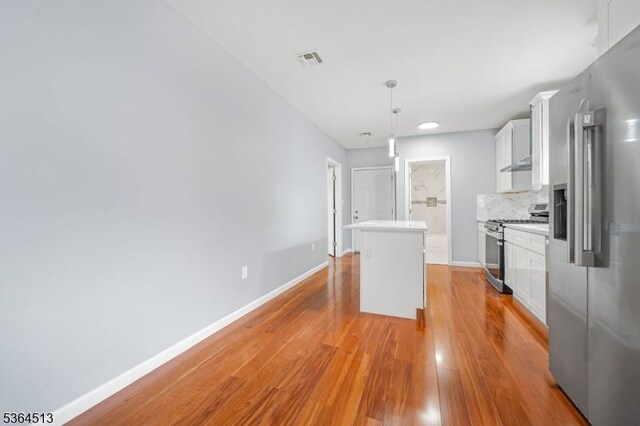 125 Birch St, Bloomfield Twp, NJ 07003 - kitchen featuring stainless steel appliances, light countertops, light wood-style flooring, white cabinetry, and decorative backsplash