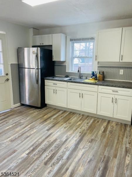 226 N 3rd Ave, Manville Boro, NJ 08835 - kitchen featuring freestanding refrigerator, dark countertops, light wood-style floors, and white cabinets