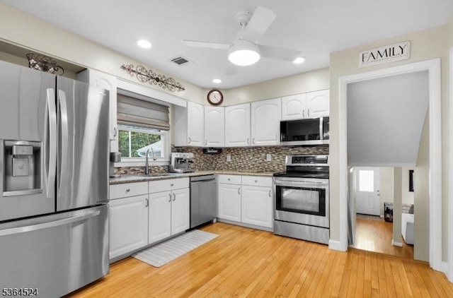 32 Sanford Dr, Randolph Twp, NJ 07869 - kitchen with stainless steel appliances, white cabinets, ceiling fan, light wood-type flooring, and backsplash