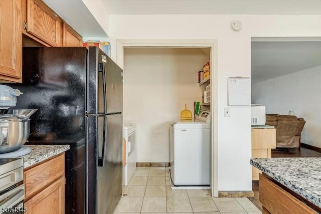 312 Cheyenne Rd Unit 312, Andover Twp, NJ 07848 - kitchen with washing machine and dryer, freestanding refrigerator, light tile patterned floors, brown cabinetry, and light stone countertops