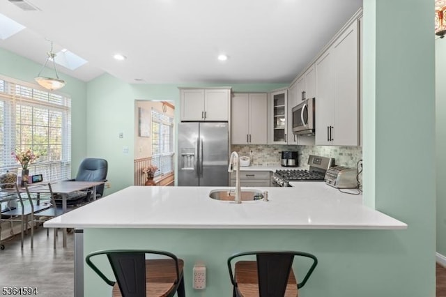 54 Magellan Way, Franklin Twp, NJ 08823 - kitchen featuring appliances with stainless steel finishes, a peninsula, a breakfast bar, tasteful backsplash, and glass insert cabinets
