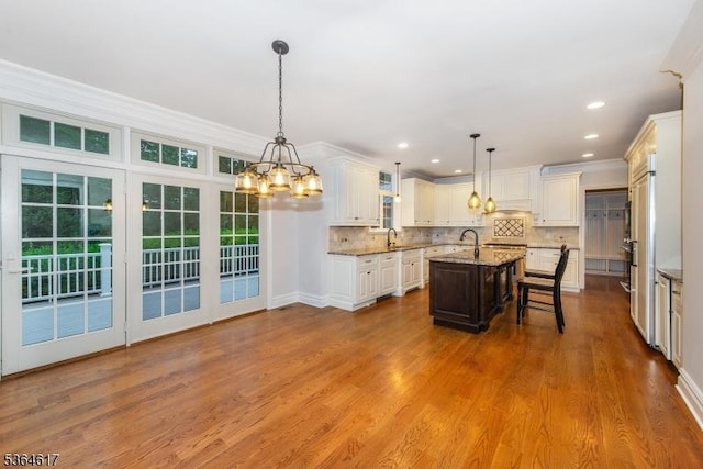 75 Keystone Ct, Bernards Twp, NJ 07920 - kitchen with a kitchen island with sink, a chandelier, tasteful backsplash, light stone counters, and white cabinetry