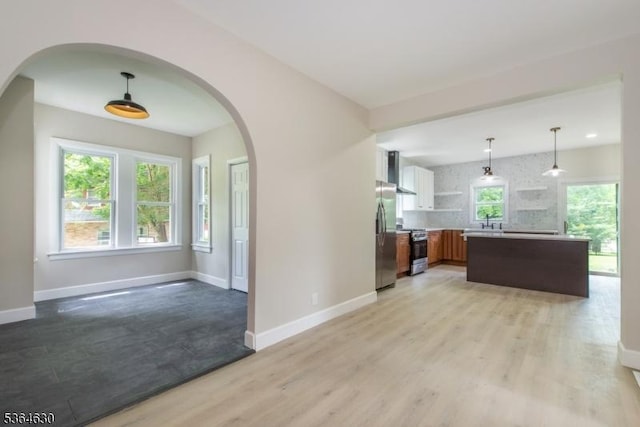 2 New Mashipacong Rd, Montague Twp, NJ 07827 - kitchen featuring appliances with stainless steel finishes, wall chimney range hood, light wood finished floors, arched walkways, and light countertops