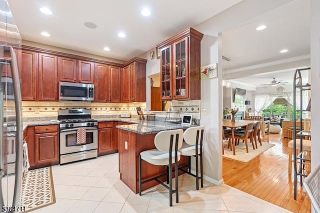 746 Green Ln, Union Twp, NJ 07083 - kitchen featuring stainless steel appliances, a peninsula, dark stone counters, crown molding, and glass insert cabinets