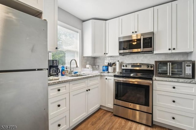 458 Midland Ave, Pompton Lakes Boro, NJ 07442 - kitchen featuring stainless steel appliances, white cabinetry, decorative backsplash, light stone counters, and light wood-style flooring