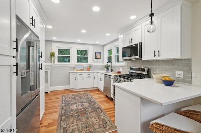 26 Saint Lawrence Ave, Maplewood Twp, NJ 07040 - kitchen with appliances with stainless steel finishes, a peninsula, light wood-type flooring, white cabinetry, and backsplash