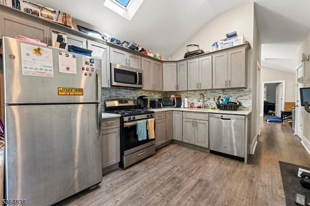 29 Pitt St, Bloomfield Twp, NJ 07003 - kitchen featuring stainless steel appliances, vaulted ceiling, a skylight, wood finished floors, and decorative backsplash