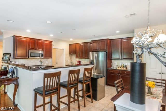 1409 Warrens Way Unit 1409, Wanaque Boro, NJ 07465 - kitchen with stainless steel appliances, dark countertops, backsplash, a peninsula, and a kitchen breakfast bar