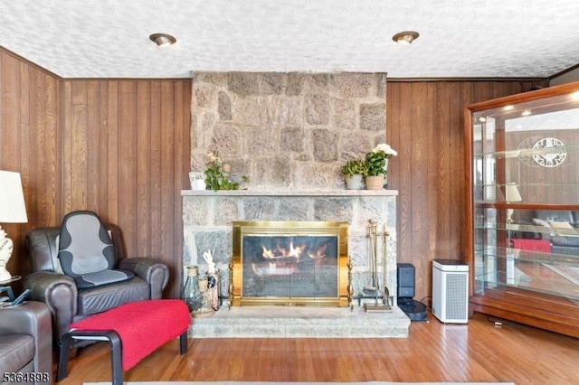 1221 Kelly St, Union Twp, NJ 07083 - living area featuring wooden walls, a stone fireplace, a textured ceiling, and wood finished floors