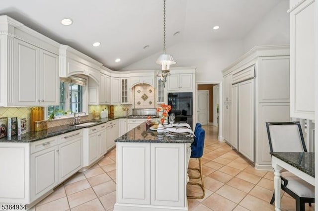 82 Mohawk Rd, Millburn Twp, NJ 07078 - kitchen with backsplash, glass insert cabinets, a breakfast bar area, lofted ceiling, and a kitchen island