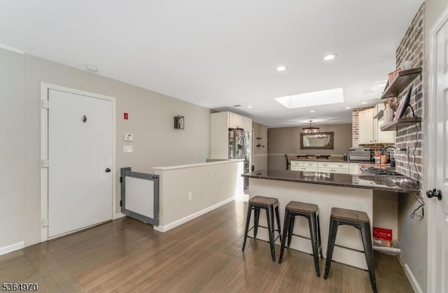 25 Old Turnpike Rd, Washington Twp, NJ 07865 - kitchen featuring a skylight, a peninsula, dark wood-style flooring, a breakfast bar, and stainless steel refrigerator with ice dispenser
