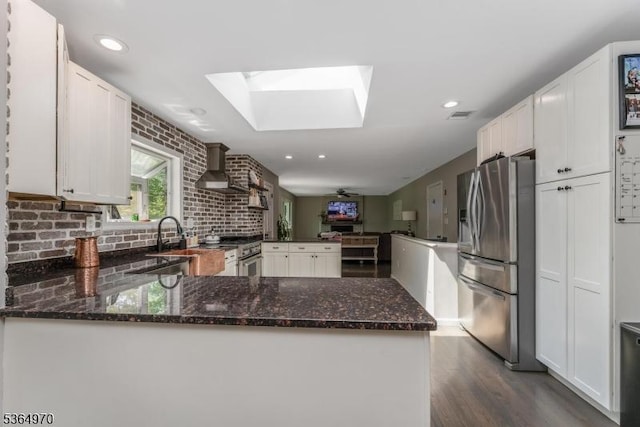 25 Old Turnpike Rd, Washington Twp, NJ 07865 - kitchen featuring appliances with stainless steel finishes, a peninsula, wall chimney exhaust hood, a skylight, and dark wood-style flooring