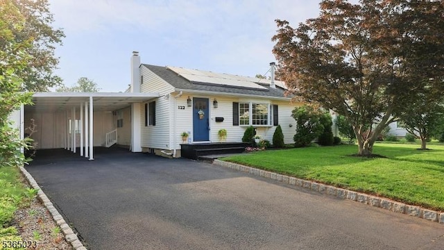 122 Madison St, South Bound Brook Boro, NJ 08880 - view of front of house with roof mounted solar panels, a front yard, an attached carport, a chimney, and driveway