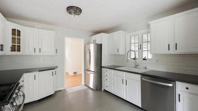 122 Madison St, South Bound Brook Boro, NJ 08880 - kitchen featuring appliances with stainless steel finishes, tasteful backsplash, dark countertops, white cabinetry, and glass insert cabinets