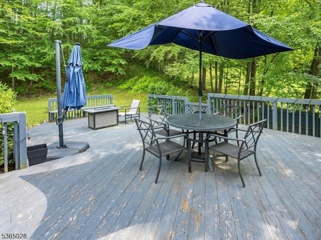 16 Seneca Trl, Randolph Twp, NJ 07869 - wooden deck featuring outdoor dining area, a wooded view, and an outdoor fire pit