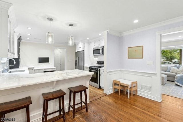 849 Bradford Ave, Westfield Town, NJ 07090 - kitchen with stainless steel appliances, a peninsula, light wood-style floors, white cabinetry, and ornamental molding