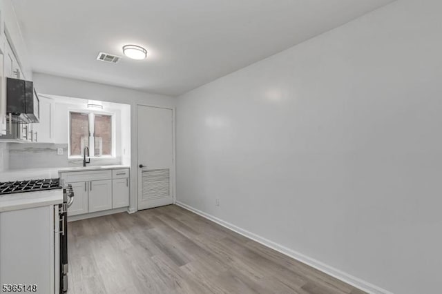 120 Westfield Ave Unit 12, Elizabeth City, NJ 07208 - kitchen featuring gas stove, light countertops, light wood-type flooring, and white cabinetry