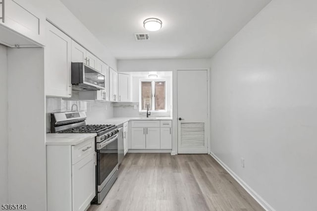 120 Westfield Ave Unit 12, Elizabeth City, NJ 07208 - kitchen with stainless steel appliances, white cabinetry, light wood-type flooring, light countertops, and tasteful backsplash