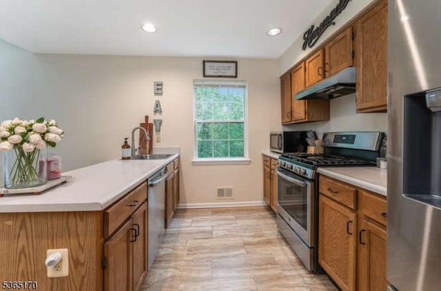 149 Wingate Dr, Independence Twp, NJ 07840 - kitchen with stainless steel appliances, under cabinet range hood, brown cabinetry, a peninsula, and light countertops