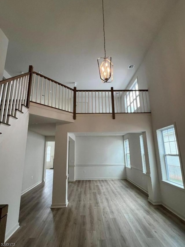 77 Norton Rd, Hillsborough Twp, NJ 08844 - unfurnished living room featuring a towering ceiling, a chandelier, wood finished floors, and stairs