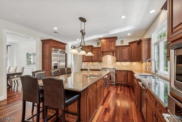 7 Sycamore Dr, Chatham Twp, NJ 07928 - kitchen with high end appliances, brown cabinetry, dark wood-style floors, light stone counters, and a breakfast bar
