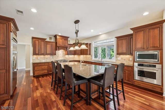7 Sycamore Dr, Chatham Twp, NJ 07928 - kitchen featuring built in appliances, a kitchen bar, dark wood-type flooring, a kitchen island with sink, and brown cabinetry