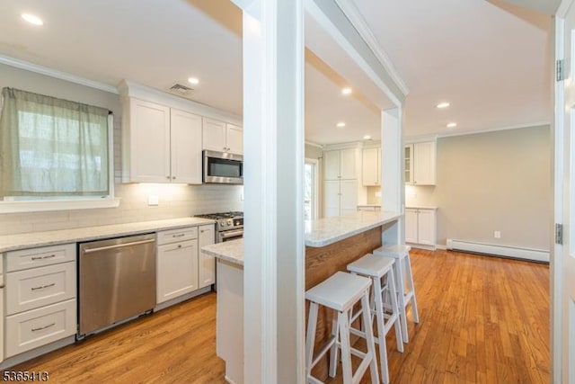 9 Hilary Ct, Vernon Twp, NJ 07460 - kitchen featuring stainless steel appliances, a baseboard radiator, ornamental molding, white cabinetry, and a kitchen bar