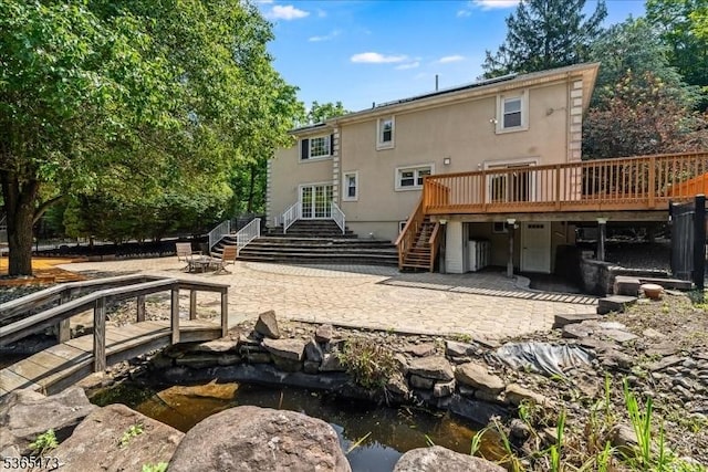 162 N Maple Ave, Bernards Twp, NJ 07920 - back of house with stairs, a patio area, a wooden deck, stucco siding, and a small pond