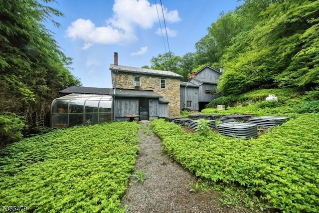 182 Musconetcong River Rd, Lebanon Twp, NJ 07882 - back of house featuring stone siding, a chimney, an outbuilding, and a greenhouse
