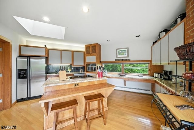 182 Musconetcong River Rd, Lebanon Twp, NJ 07882 - kitchen featuring stainless steel refrigerator with ice dispenser, a baseboard heating unit, light wood finished floors, a skylight, and backsplash