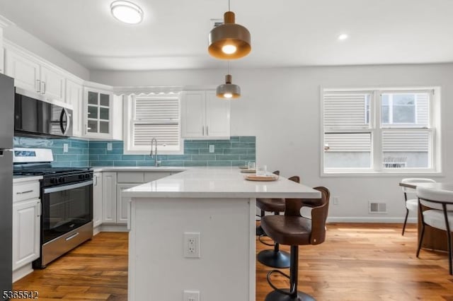 98 S Burnett St, East Orange City, NJ 07018 - kitchen featuring appliances with stainless steel finishes, a breakfast bar, tasteful backsplash, and light wood finished floors