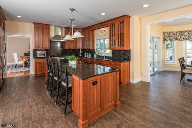 4 Wingover Farm Ct, Raritan Twp, NJ 08822 - kitchen with wall chimney range hood, brown cabinets, a center island, decorative backsplash, and glass insert cabinets