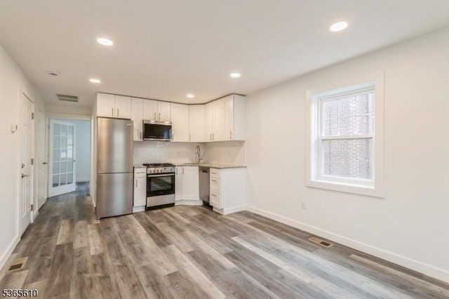 1489 Morris Ave, Union Twp, NJ 07083 - kitchen featuring appliances with stainless steel finishes, backsplash, white cabinets, wood finished floors, and recessed lighting