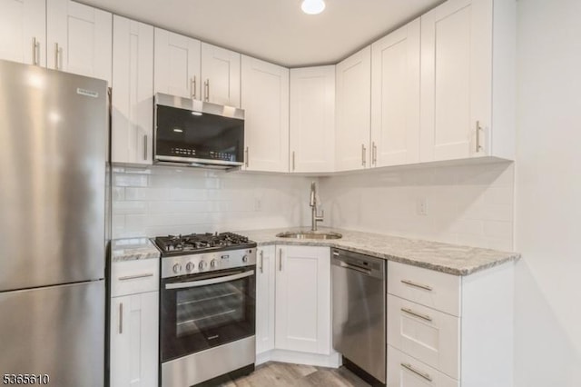 1489 Morris Ave, Union Twp, NJ 07083 - kitchen with appliances with stainless steel finishes, white cabinets, light stone counters, backsplash, and light wood-style floors