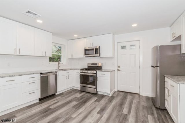 1489 Morris Ave, Union Twp, NJ 07083 - kitchen featuring appliances with stainless steel finishes, white cabinets, wood finished floors, recessed lighting, and light stone countertops