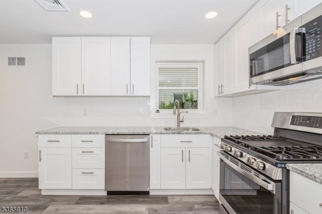 1489 Morris Ave, Union Twp, NJ 07083 - kitchen with appliances with stainless steel finishes, backsplash, light stone countertops, recessed lighting, and wood finished floors