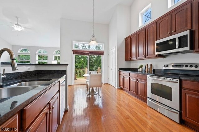 7 Thornton St, Hillsborough Twp, NJ 08844 - kitchen featuring stainless steel appliances, high vaulted ceiling, light wood-style flooring, pendant lighting, and dark stone countertops