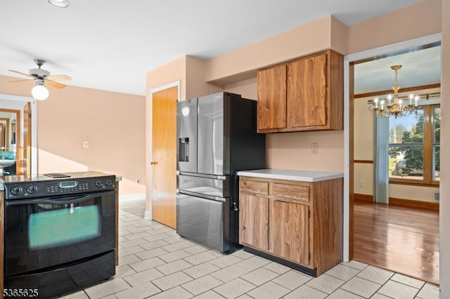 1265 Iris St, North Brunswick Twp, NJ 08902 - kitchen featuring black electric range, stainless steel fridge, brown cabinetry, light countertops, and a chandelier