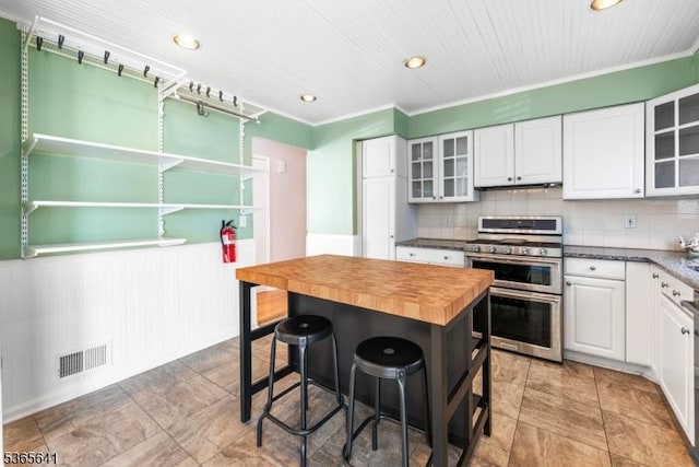 9 Village Ct, Flemington Boro, NJ 08822 - kitchen featuring double oven range, butcher block countertops, white cabinetry, a wainscoted wall, and a breakfast bar area
