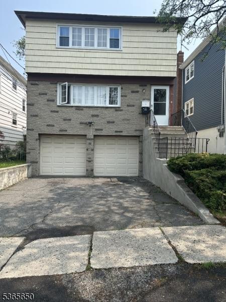 73 Berkeley Ter, Irvington Twp, NJ 07111 - back of property with a garage, asphalt driveway, and stone siding