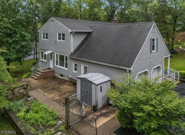 708 Carlene Dr, Bridgewater Twp, NJ 08807 - rear view of house featuring roof with shingles, a storage shed, a chimney, view of scattered trees, and a garage