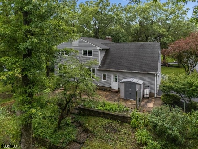 708 Carlene Dr, Bridgewater Twp, NJ 08807 - back of house with a shed, roof with shingles, a chimney, and view of wooded area
