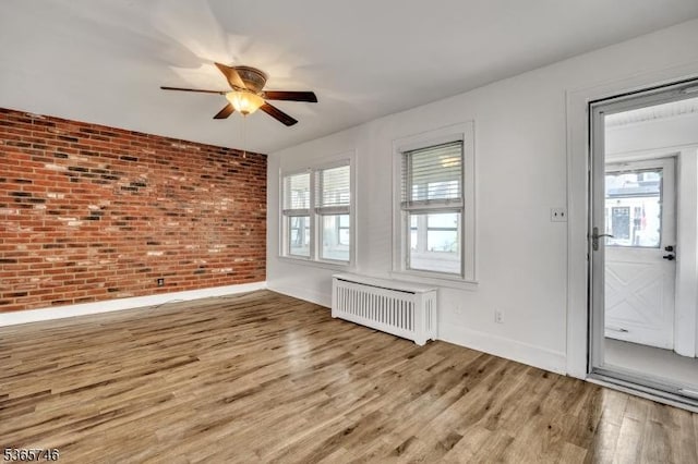 522 Locust Ave, Hillside Twp, NJ 07205 - spare room with radiator heating unit, a ceiling fan, brick wall, and wood finished floors