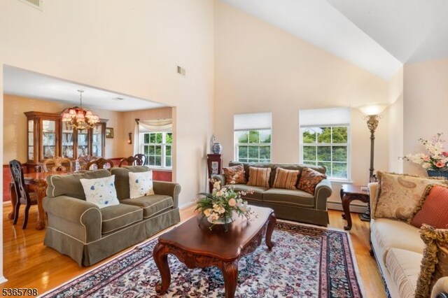 12 Autumn Dr, Mine Hill Twp, NJ 07803 - living area with light wood-type flooring, a baseboard heating unit, a chandelier, and high vaulted ceiling