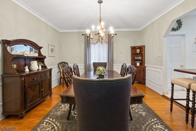 905 Dewitt St, Linden City, NJ 07036 - dining area with a chandelier, light wood-style flooring, crown molding, arched walkways, and a wainscoted wall