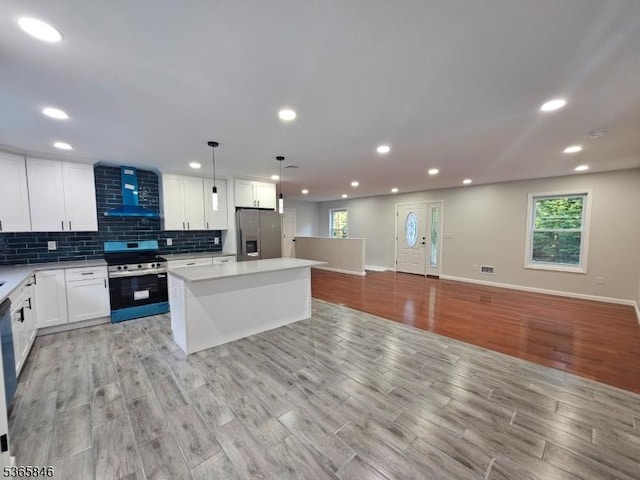 43 Rockport Rd, Wantage Twp, NJ 07461 - kitchen with stainless steel appliances, wall chimney range hood, light wood-style floors, white cabinetry, and plenty of natural light