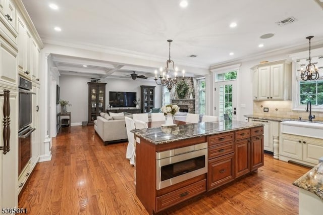 27 Wesley Ct, New Providence Boro, NJ 07974 - kitchen with appliances with stainless steel finishes, a chandelier, a ceiling fan, a large fireplace, and stone counters
