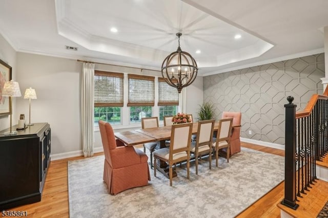 27 Wesley Ct, New Providence Boro, NJ 07974 - dining area with a raised ceiling, a chandelier, light wood finished floors, ornamental molding, and an accent wall