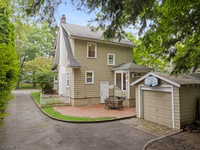 72 Meadowbrook Rd, Millburn Twp, NJ 07078 - view of front facade with an outbuilding, roof with shingles, a chimney, a detached garage, and driveway